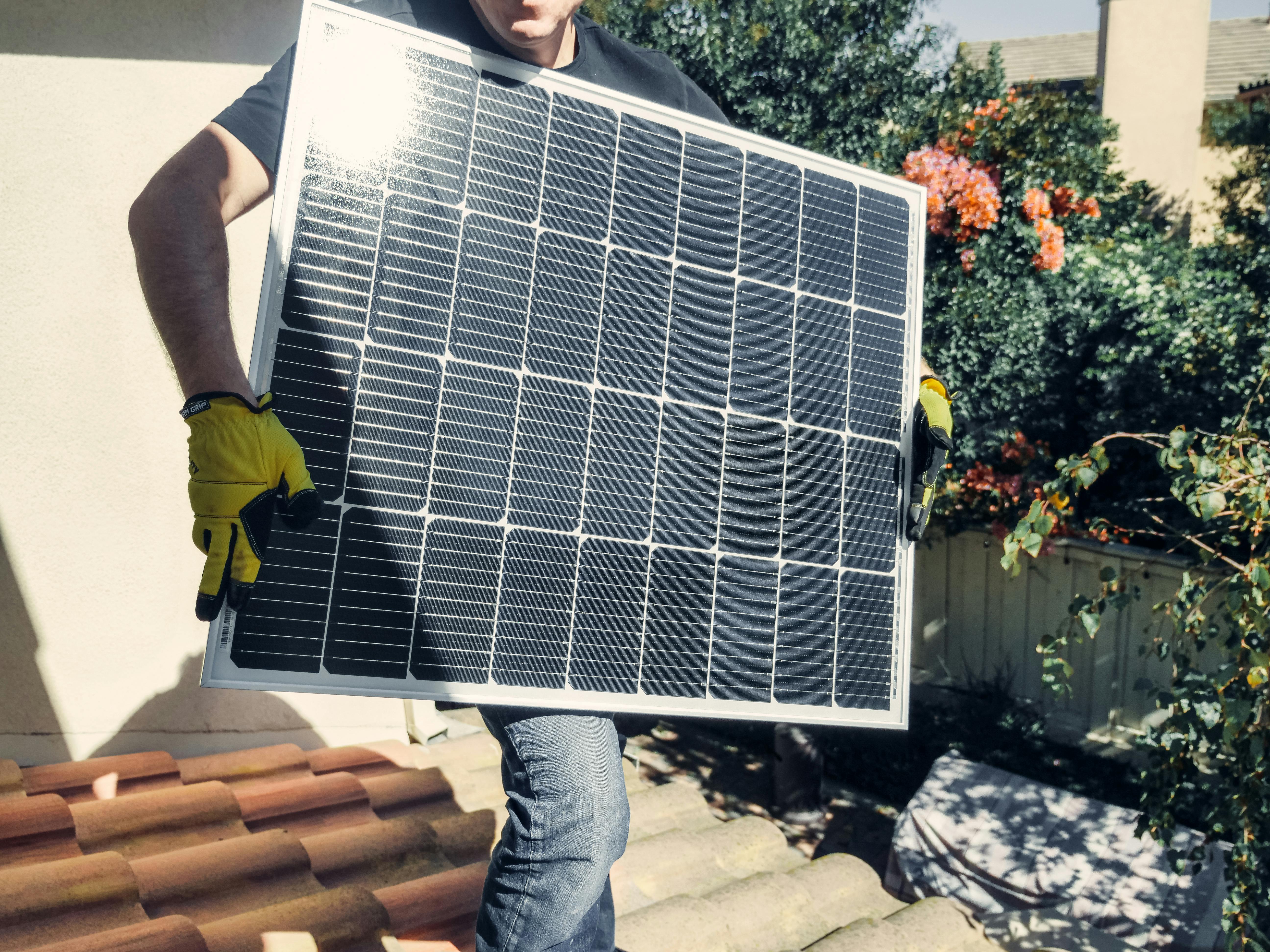 Rayenna technician carrying a solar panel for rooftop installation